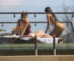 Kim and Khloe Kardashian relax poolside on their Costa Rican vacation. Kim wore a nude bikini while Khloe opted for a burgundy one-piece. Kris was also seen walking around the luxury property the family have rented.